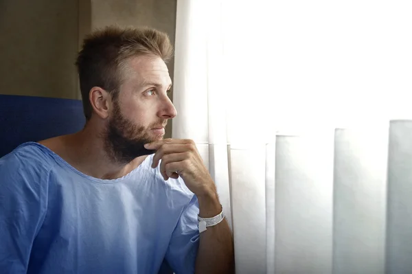 Young injured man in hospital room sitting alone in pain worried for his health condition