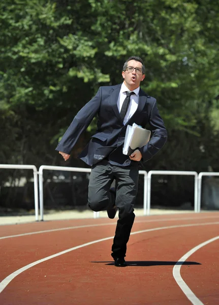 Businessman in suit and necktie carrying folder running desperate in stress on athletic track