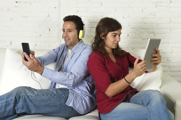 Couple on couch ignoring each other using mobile phone and digital tablet in internet addiction