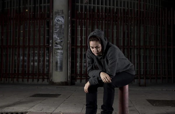 Sad woman alone on street suffering depression desperate and helpless wearing hoodie