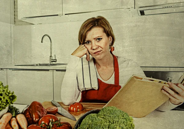 Cook woman bored and frustrated reading recipes book in home kitchen in stress