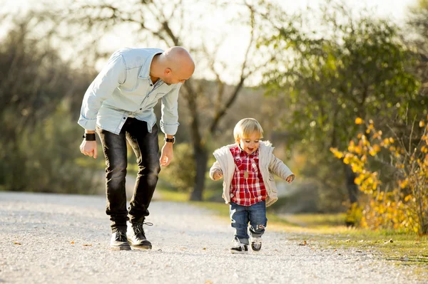 Young father and his beautiful little 2 years old son walking together in the park