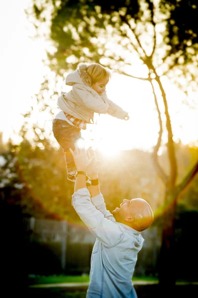 Young happy man playing with excited little cute son throwing the kid in the air