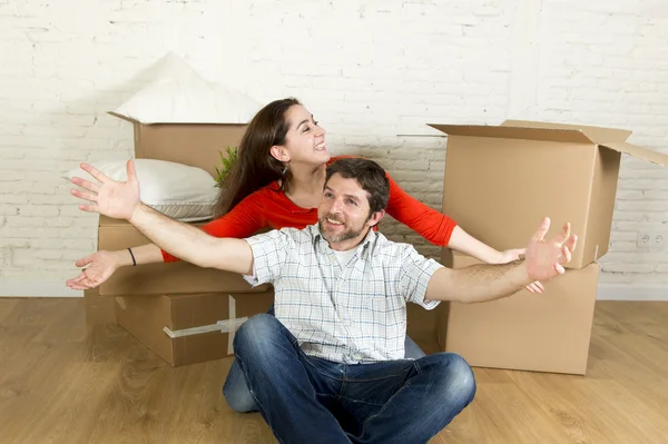 Young happy couple sitting on floor together celebrating moving in new flat house or apartment