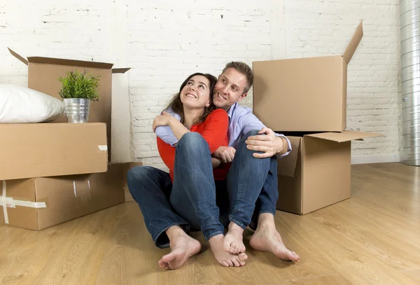 Happy couple sitting on floor celebrating moving in new flat house or apartment