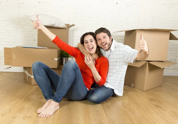 Happy couple sitting on floor celebrating moving in new flat house or apartment