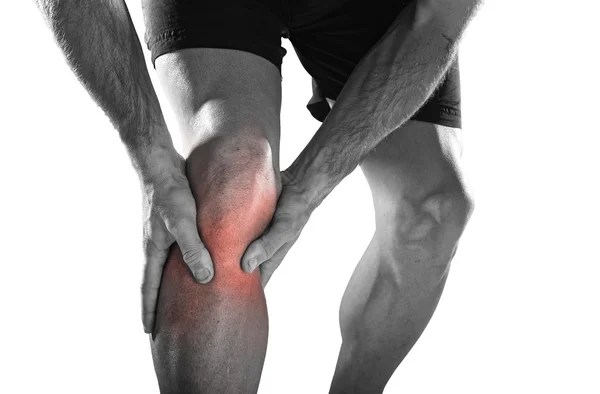 Young sport man with athletic legs holding knee with hands in pain after suffering injury running