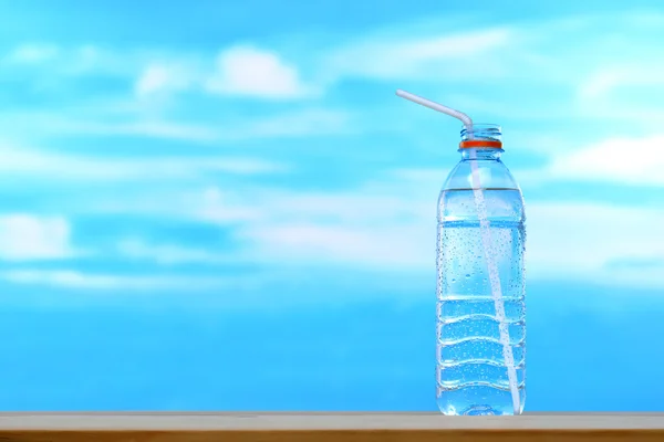 Fresh and clean drinking water in bottle with straw on sky background