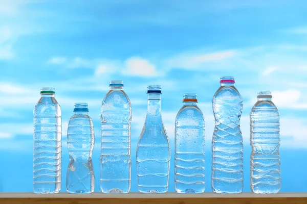 Fresh and clean drinking water in assortment of uncapped bottles with water droplet on sky background