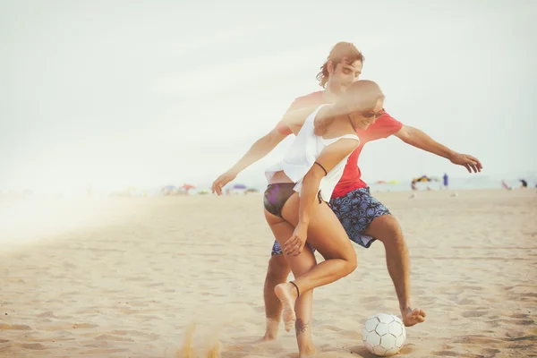 Young couple playing football on the beach with analog film effe