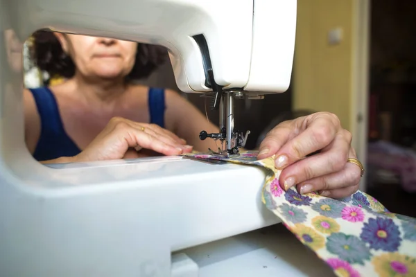 Middle aged woman using a sewing machine electric