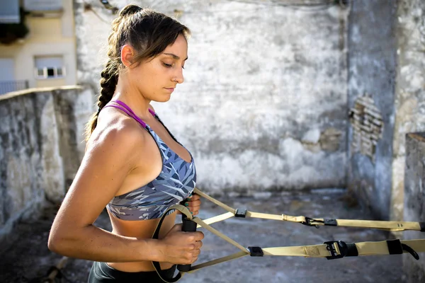 Woman practicing Suspension training on an old rooftop