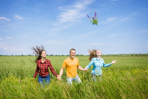 Young happy Friends running on green wheat field