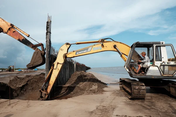 Excavator build breakwater at beach