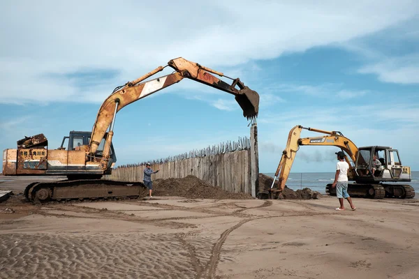 Excavator build breakwater at beach