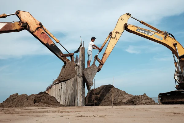 Excavator build breakwater at beach