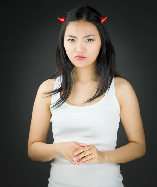 Serious Asian young woman in devil horns looking angry