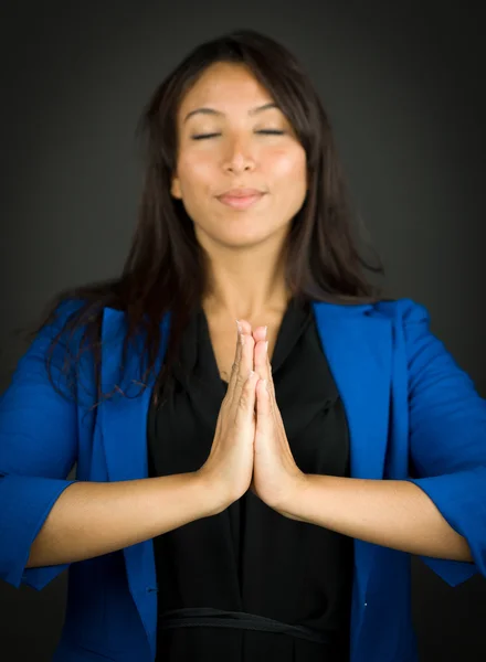 Young businesswoman in prayer position with her hands clasped meditating