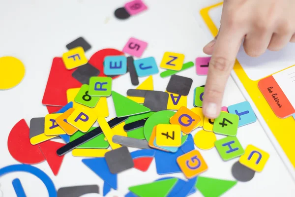 Close up of a persons hand showing multi-coloured alphabet puzzle pieces