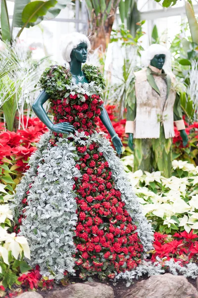 Statue wearing clothes made of colorful Christmas flowers displayed at Allan Gardens, Toronto, Ontario, Canada