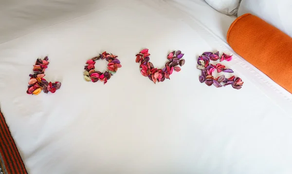 Word \'love\' made out of flower petals on bed