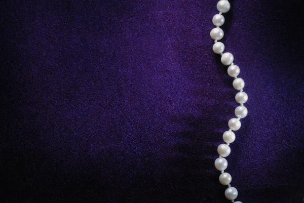 Pearl beads on purple velvet background