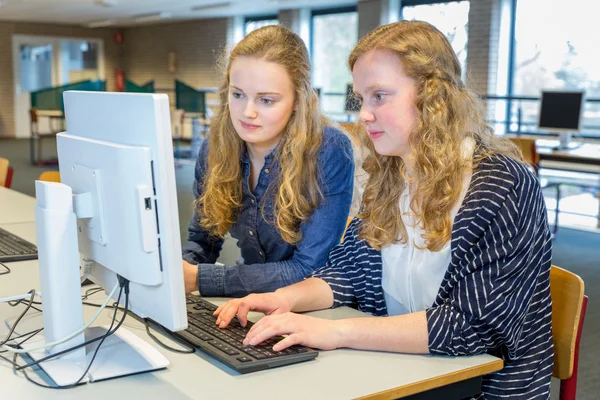 Two female students working together on computer in classroom