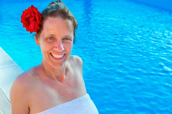 Caucasian woman with rose and towel at swimming pool