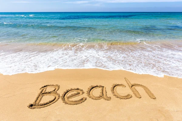 Word Beach written in sand at greek sea