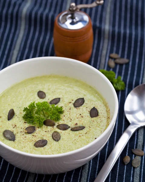 Homemade green broccoli cream soup served in white bowl