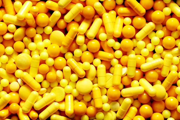 Yellow medicinal pills piled up a bunch of closeup