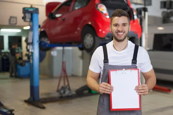 Mechanic in auto repair shop showing blank clipboard