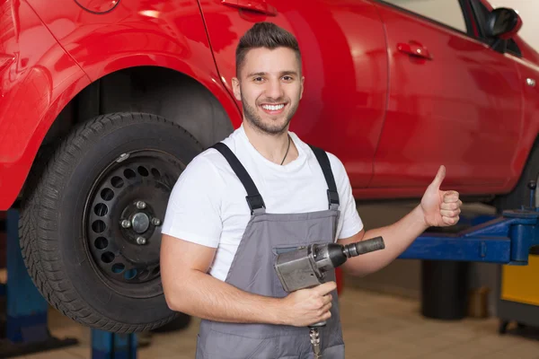 Mechanic holding an impact wrench and showing thumb up