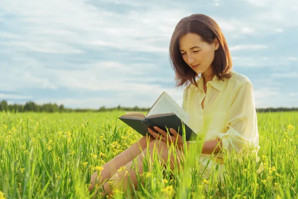 Girl reading book on meadow
