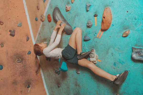 Girl exercises on artificial boulders wall
