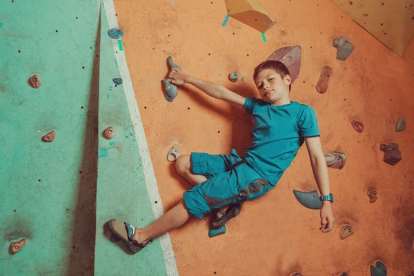 Boy climbing on artificial boulders wall