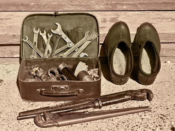 Suitcase with plumbing tools and galoshes