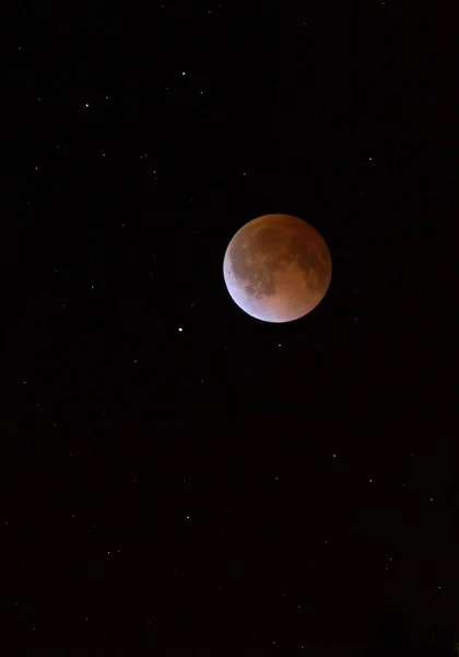 This is a photograph of the Lunar Eclipse Blood Moon moving out of its maximum stage at 3:00am Central Time. Background star field added from same sky location later.