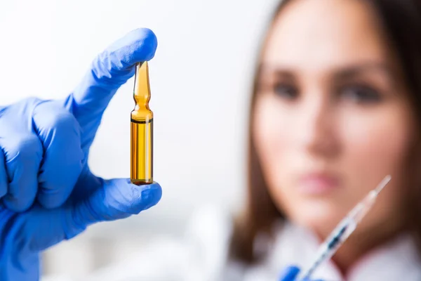 Doctor with hand in medical glove holding syringe and ampoule, blurred look. Concept of medical help.