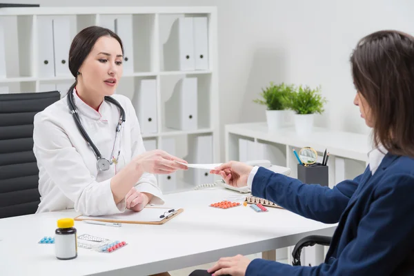 Doctor giving prescription to patient. Pills on table. Medical office. Concept of medical consultation.