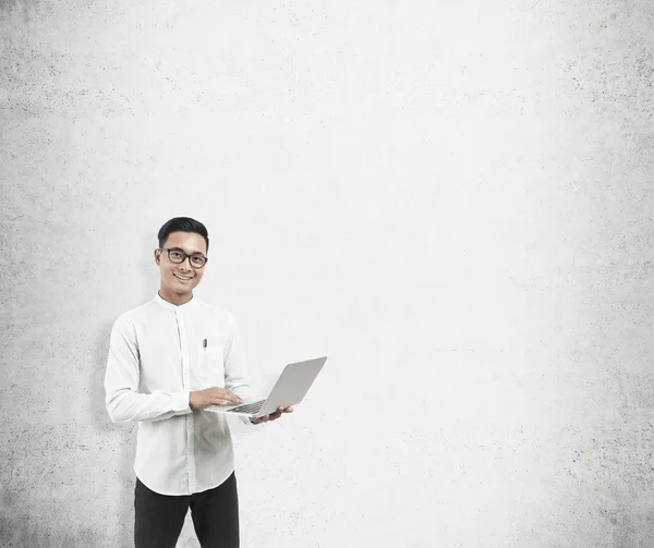Asian man with laptop and concrete wall