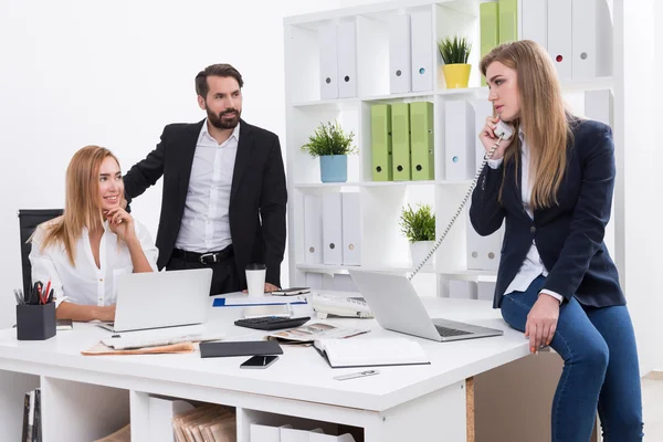 Office interior. Man and woman are waiting for their colleague to finish her phone talk with investors. Firm\'s future is at stake. Concept of business negotiations.
