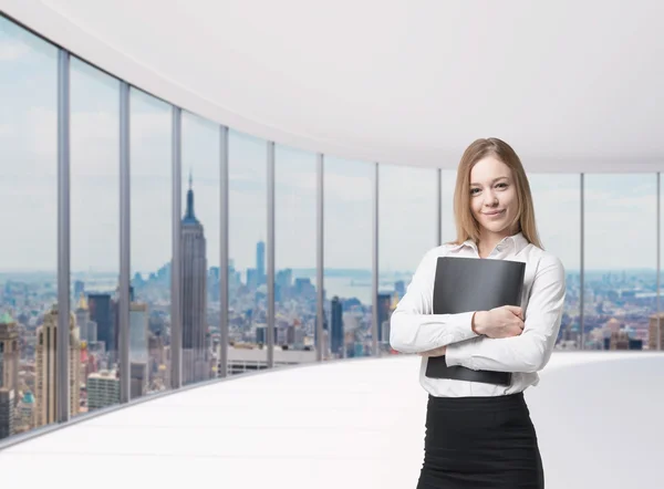 Young beautiful business lady is holding a black document case. New York panoramic office. A concept of legal services.