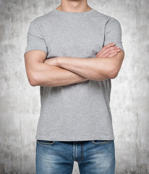 Man wearing grey t-shirt with crossed hands, Isolated on concrete background.