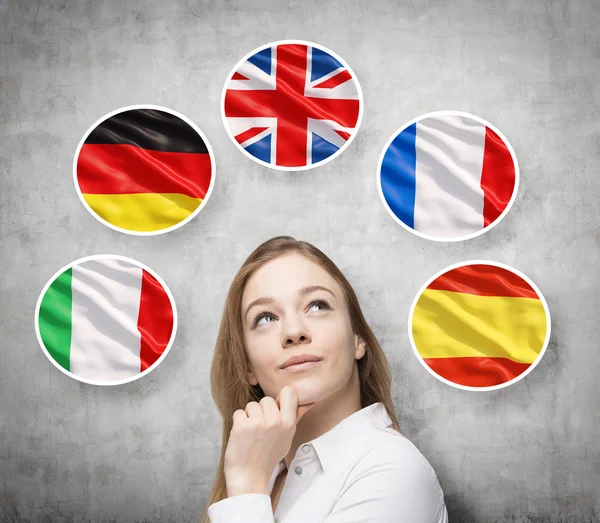 Beautiful lady is surrounded by bubbles with european countries\' flags (Italian, German, Great Britain, French, Spanish). Learning of foreign languages concept. Concrete background.