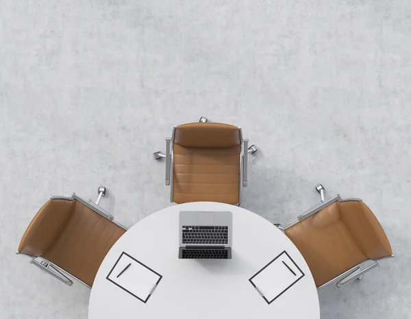 Top view of a half of the conference room. A white round table, three brown leather chairs. A laptop with legal pads are on the table. Office interior. 3D rendering.