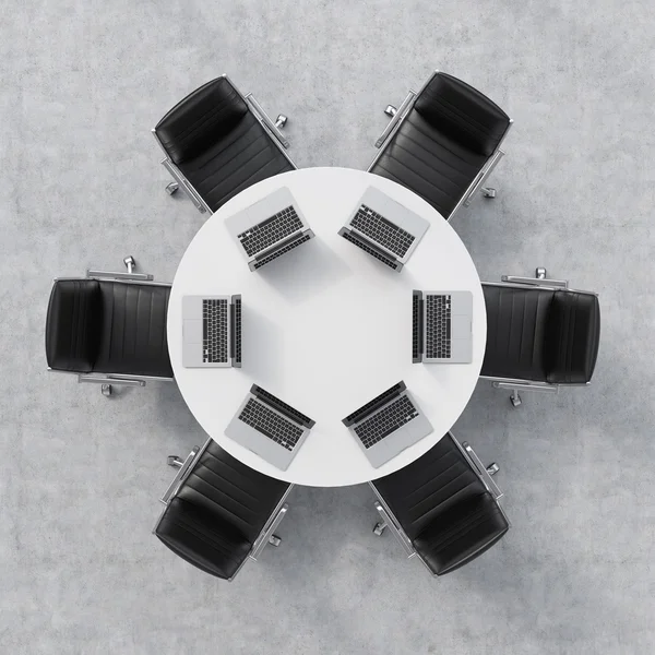 Top view of a conference room. A white round table, six chairs. Six laptops are on the table. Office interior. 3D rendering.