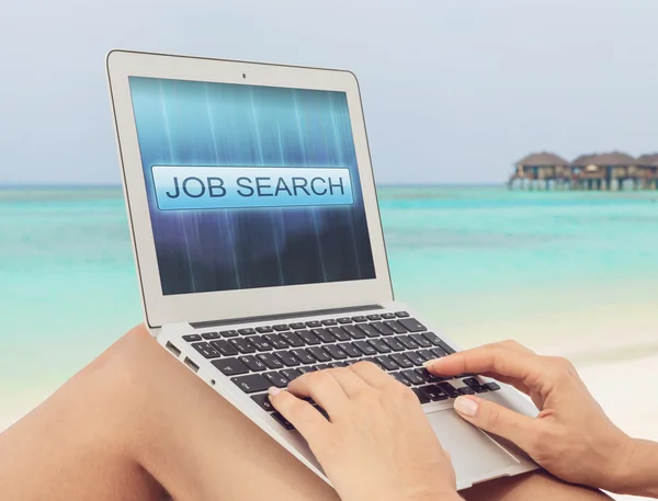 Woman on the tropical beach is looking for a job using a laptop. Internet Job Search concept on the laptop's screen. Freelance as a mainstream.