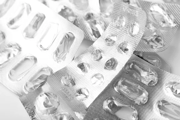 Pile of empty medicine blister packs on white surface.