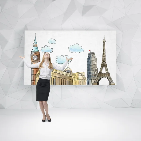 A happy beautiful woman is looking up and dreaming about the visiting of the most famous European cities. Sketches of European cities are drawn on the whiteboard. Contemporary wall.
